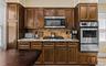 Kitchen with stainless steel appliances, backsplash, a warming drawer, light stone countertops, and light wood-type flooring
