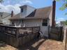 Rear view of property with a shingled roof, a deck, and a chimney
