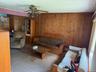 Carpeted living area featuring wooden walls and a ceiling fan