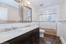 Bathroom featuring bath / shower combo with glass door, tile walls, a baseboard heating unit, and dark tile patterned floors
