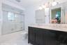 Bathroom with tile walls, connected bathroom, enclosed tub / shower combo, and light tile patterned floors