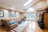 Living area with high vaulted ceiling, a skylight, wood finished floors, recessed lighting, and french doors