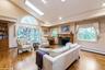 Living room with high vaulted ceiling, a skylight, light wood finished floors, a premium fireplace, and a baseboard radiator