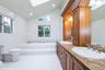 Bathroom with a skylight, lofted ceiling, a bath, light tile patterned flooring, and recessed lighting