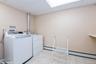 Laundry room with light tile patterned floors, separate washer and dryer, and a baseboard radiator