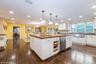 Kitchen featuring backsplash, a chandelier, white cabinets, decorative light fixtures, and dark wood-style floors