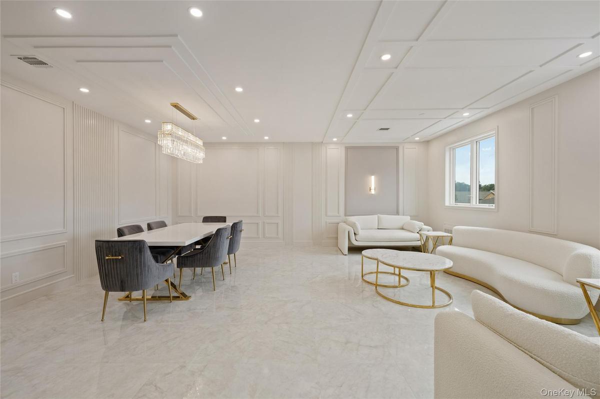 Living area with a decorative wall, recessed lighting, and light marble finish flooring
