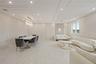 Living area with a decorative wall, recessed lighting, and light marble finish flooring