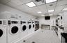 Communal laundry room featuring stacked washing machine and dryer, washer and clothes dryer, and tile patterned flooring