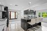 Kitchen with light marble finish flooring, recessed lighting, glass insert cabinets, pendant lighting, and wall chimney exhaust hood