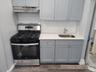 Apt 3 Rear Kitchen with dark wood-type flooring, under cabinet range hood, stainless steel range with gas stovetop, a sink, and gray cabinetry