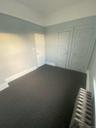Unfurnished bedroom featuring dark colored carpet, baseboards, and radiator