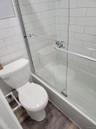 Full bath with combined bath / shower with glass door, wood finished floors, and toilet