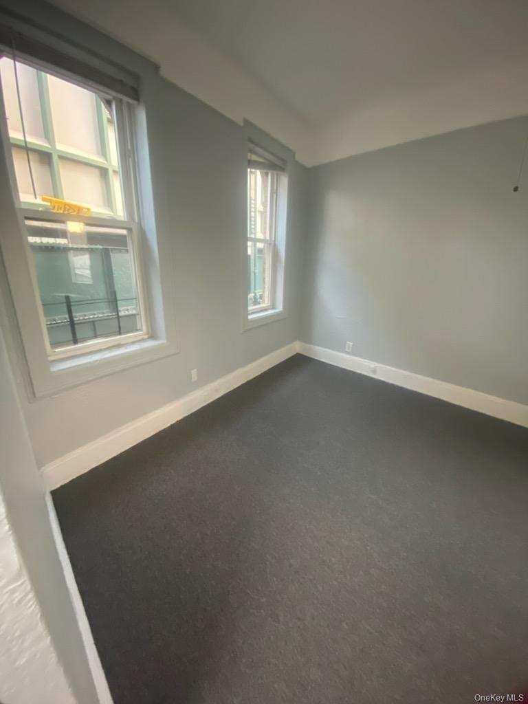 Carpeted spare room featuring baseboards