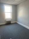 Empty room featuring baseboards, radiator, and dark colored carpet