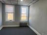 Spare room featuring a textured wall, a paneled ceiling, radiator heating unit, dark carpet, and baseboards