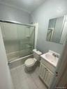 Bathroom with tile patterned flooring, bath / shower combo with glass door, toilet, and vanity