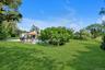 View of grassy yard featuring an outdoor pool, a gazebo, and view of scattered trees