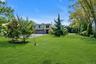 View of grassy yard with an attached garage and driveway