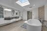 Primary  bath with a skylight, double vanity, a freestanding bath, a shower stall, and woodlike finished floors