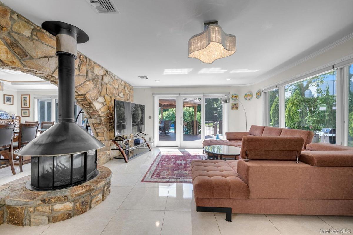 Family room featuring ornamental molding, healthy amount of natural light, light tile patterned floors, and a wood burning fireplace