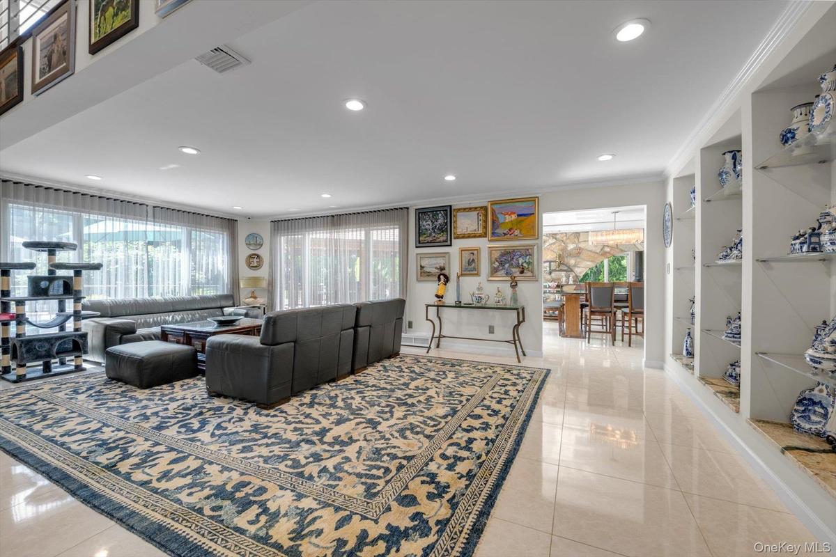 Living Room with plenty of natural light, light tile patterned floors, recessed lighting, and crown molding