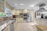 Kitchen featuring Wood cabinets, wall chimney range hood, stainless steel appliances, backsplash, and island with seating