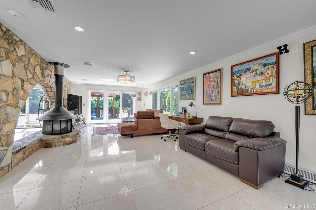 Family room with a wood Burning Fireplace, light tile patterned flooring, recessed lighting, ornamental molding, and a doors to Deck