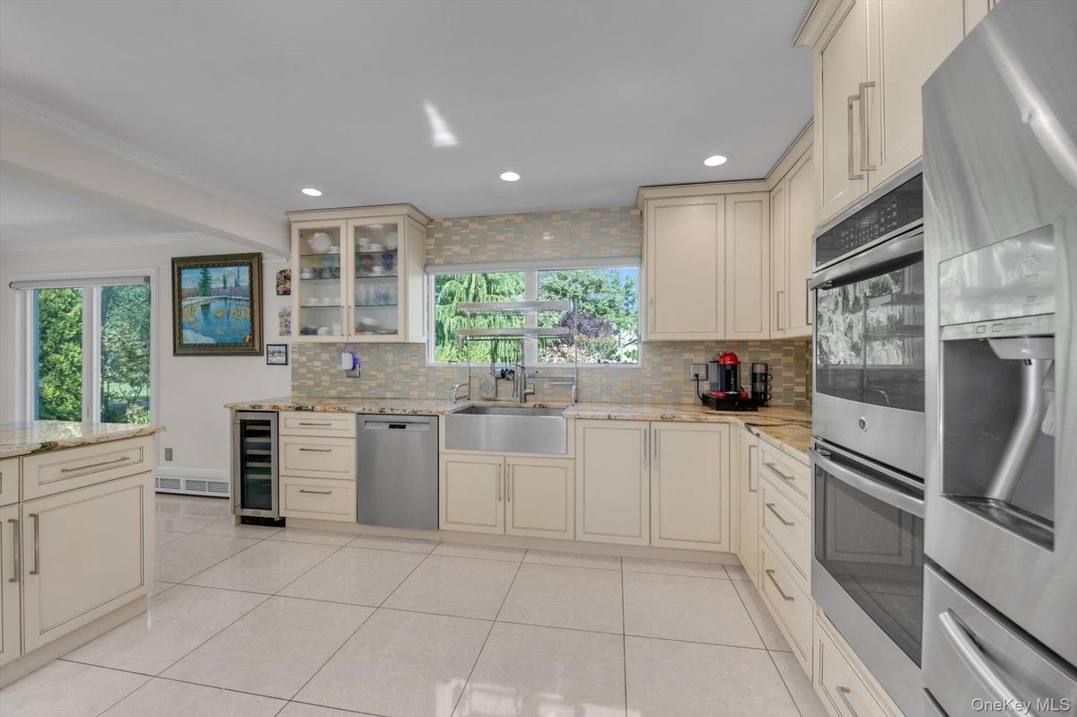 Kitchen with wood cabinets, tasteful backsplash, stainless steel appliances, light tile patterned floors, and recessed lighting