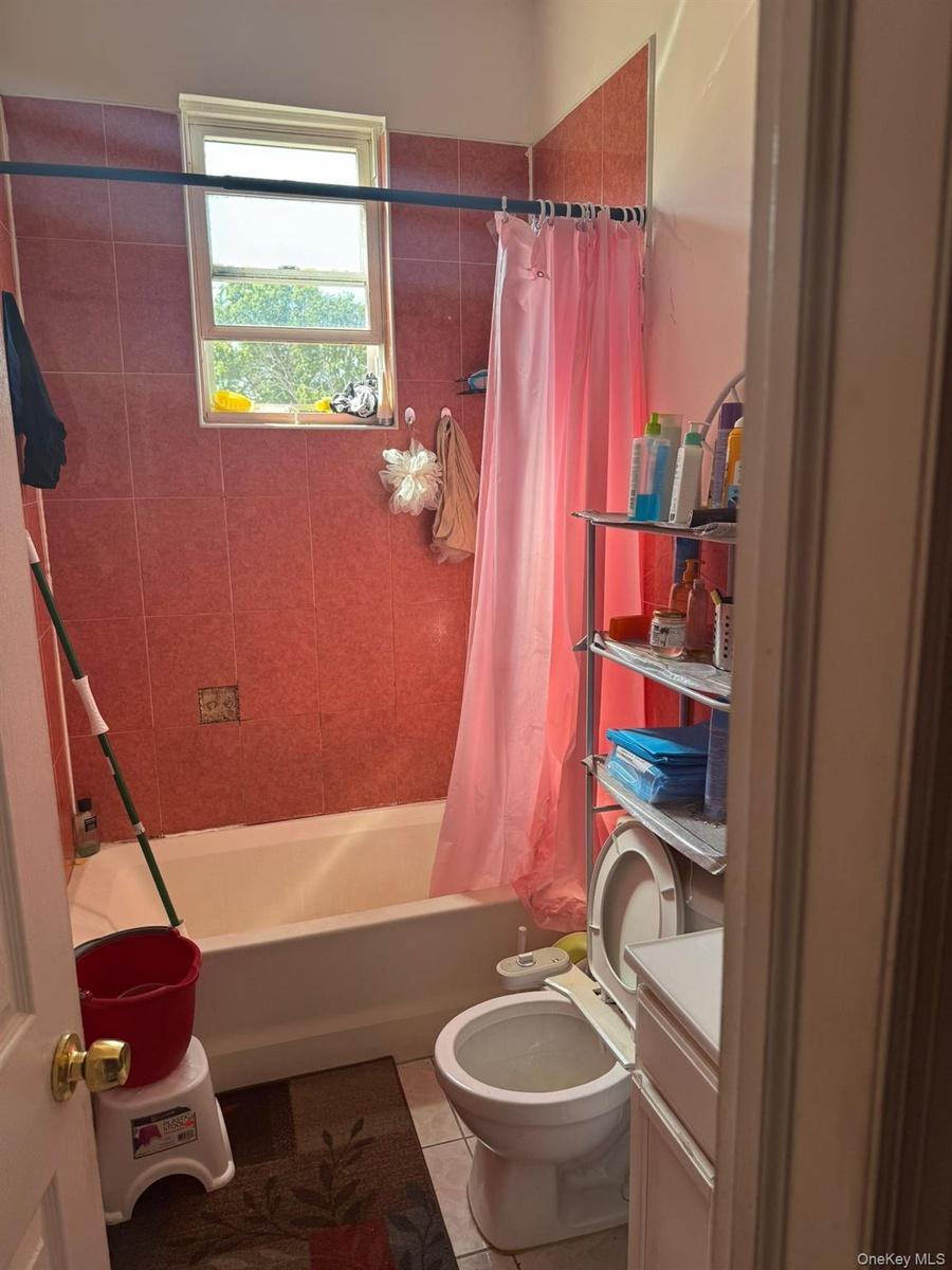 Bathroom featuring shower / bathtub combination with curtain, vanity, and light tile patterned floors
