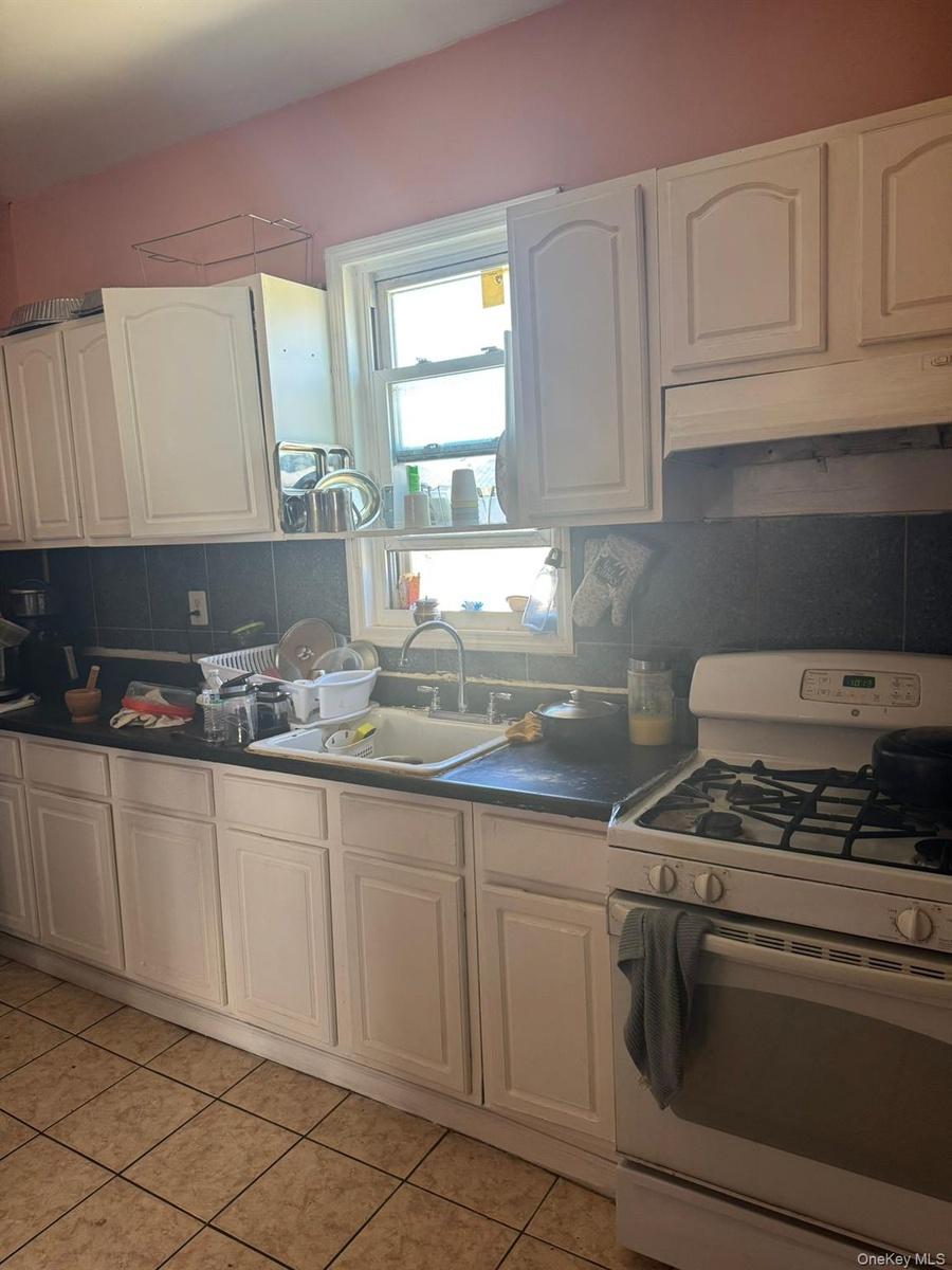 Kitchen with gas range gas stove, decorative backsplash, white cabinets, and dark countertops