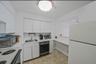 Kitchen featuring white appliances, light countertops, and white cabinets
