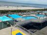 Community pool featuring a patio and view of water and beach