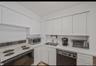 Kitchen featuring white electric range, light countertops, dishwasher, white cabinetry, and stainless steel microwave