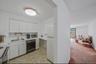 Kitchen featuring light countertops, light colored carpet, white cabinets, and white appliances