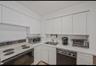 Kitchen featuring range with electric cooktop, dishwasher, light countertops, white cabinetry, and stainless steel microwave