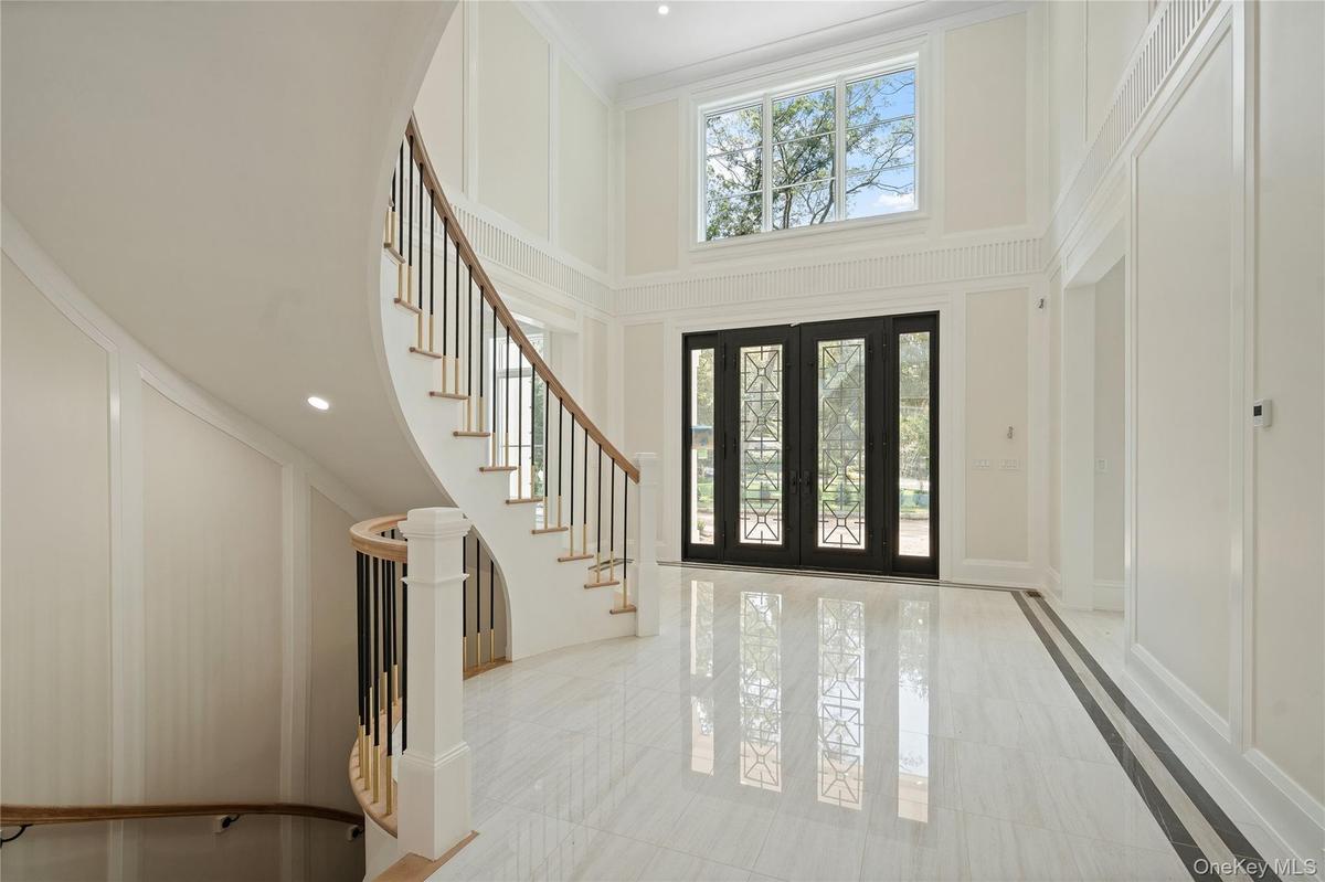 Foyer entrance featuring french doors, plenty of natural light, a decorative wall, a high ceiling, and recessed lighting