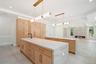 Kitchen with light brown cabinets, hanging light fixtures, light stone counters, beam ceiling, and recessed lighting