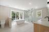 Bathroom featuring a stall shower, a freestanding bath, double vanity, recessed lighting, and tile walls