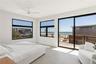 Bedroom featuring view of water and beach, access to exterior, and a ceiling fan