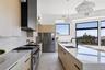 Kitchen with light brown cabinets, stainless steel appliances, light stone countertops, modern cabinets, and decorative backsplash