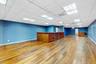 Empty room with light wood-style floors, a community bar, and a drop ceiling