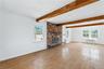 Unfurnished living room featuring hardwood / wood-style floors, radiator heating unit, a brick fireplace, and beam ceiling