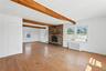 Unfurnished living room featuring light wood finished floors, beamed ceiling, radiator heating unit, and a fireplace