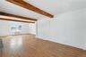 Unfurnished living room featuring wood-type flooring, beamed ceiling, and radiator