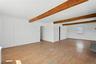 Spare room with light wood-style floors, arched walkways, and beamed ceiling