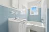 Bathroom with bathing tub / shower combination, tile walls, vanity, and wainscoting