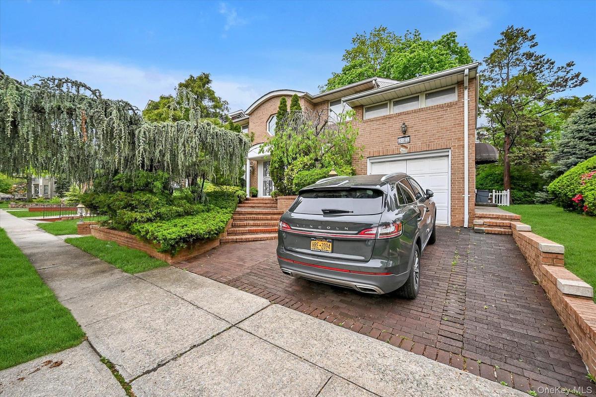 View of front facade with driveway, brick siding, and a garage