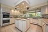Kitchen featuring light tile patterned floors, recessed lighting, stainless steel appliances, a kitchen island, and light stone counters