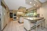 Kitchen with light tile patterned flooring, recessed lighting, a breakfast bar area, light stone counters, and a peninsula